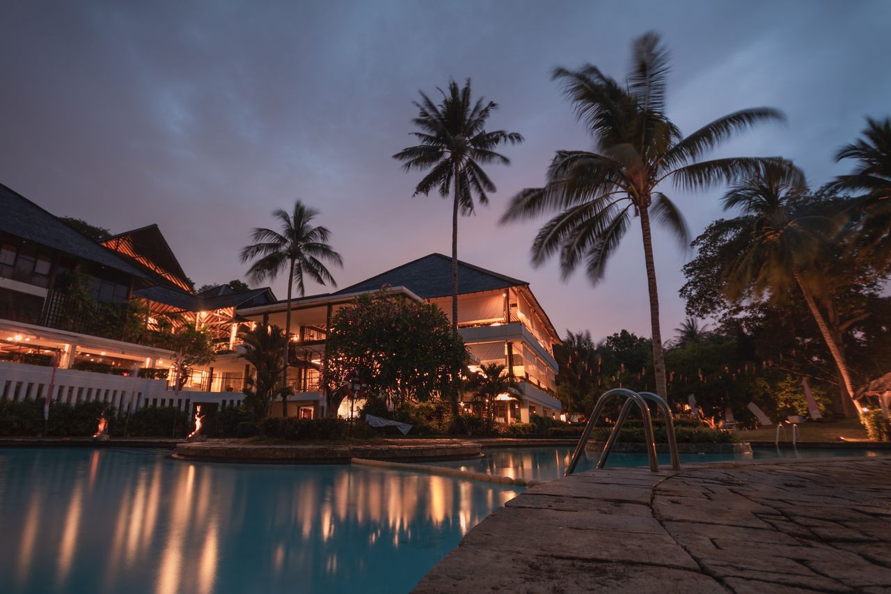 Luxurious tropical resort with swimming pool and palms at dusk