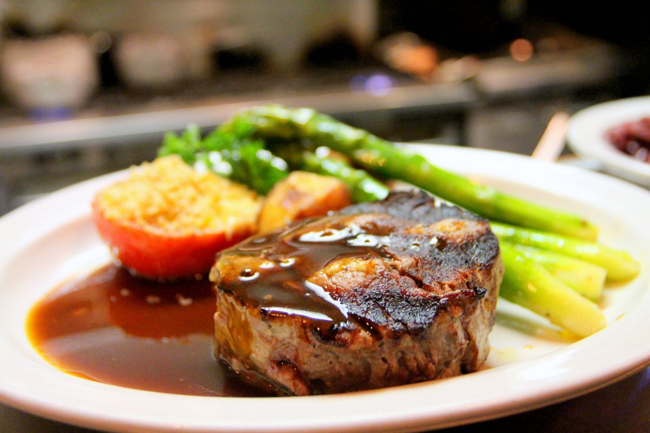 Delicious grilled steak with asparagus and tomato served with rich sauce on a plate