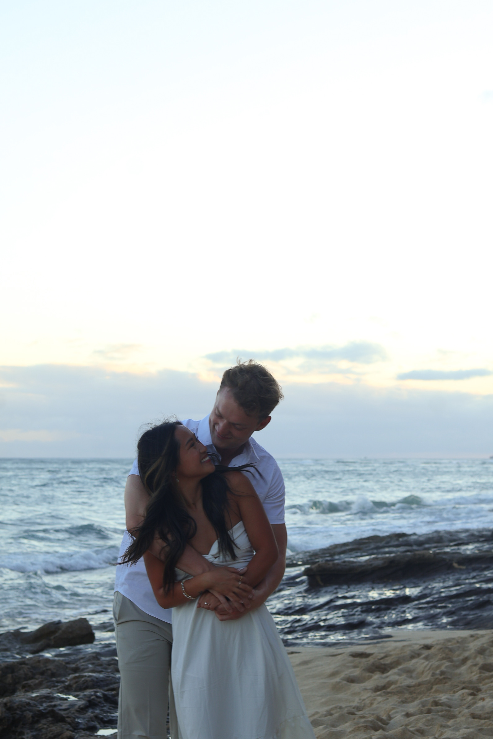 Couple embracing at lighthouse at golden hour with scenic landscape backdrop